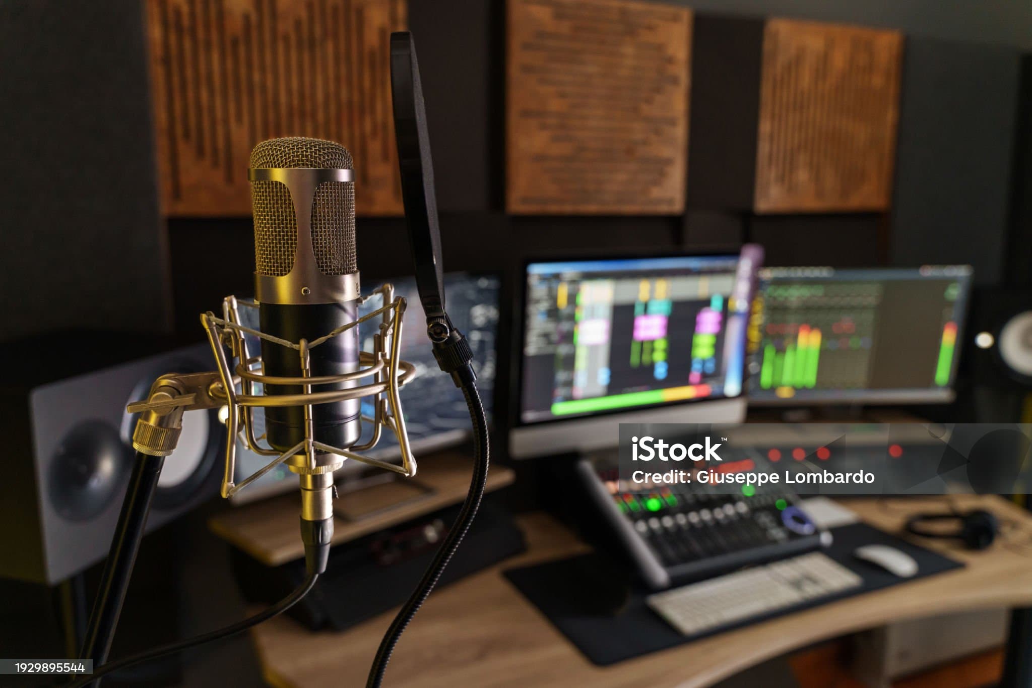 Studio microphone in front of a mixing desk and audio meters